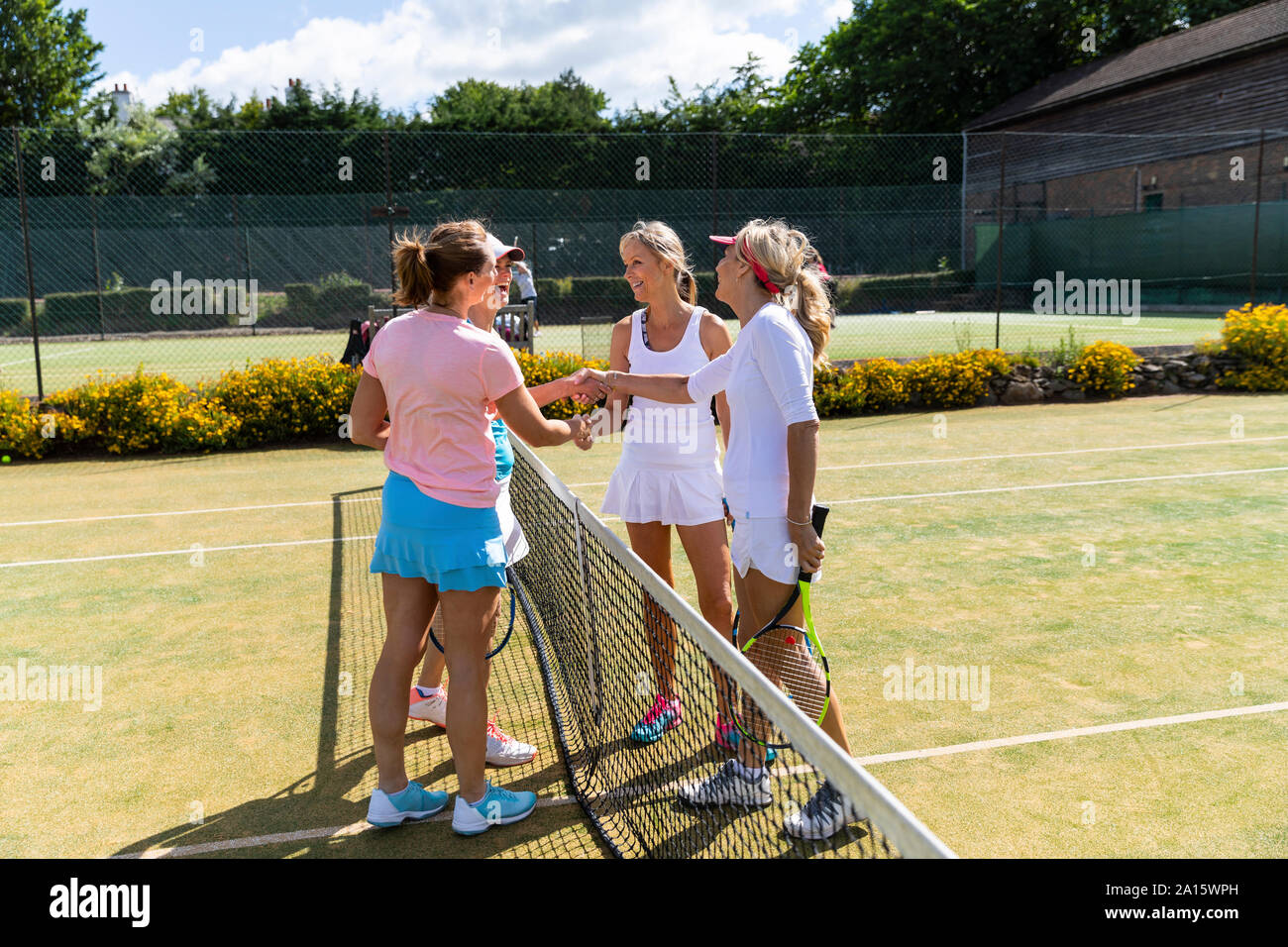 Reife Frauen finishing Tennismatch auf Gras Gericht Hände schütteln Stockfoto