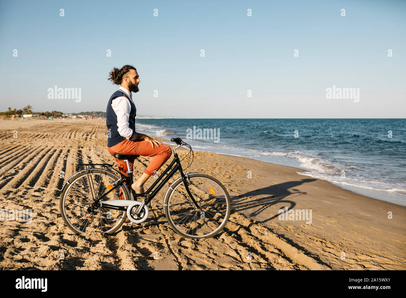 Gut gekleideter Mann mit seinem Fahrrad am Strand Stockfoto