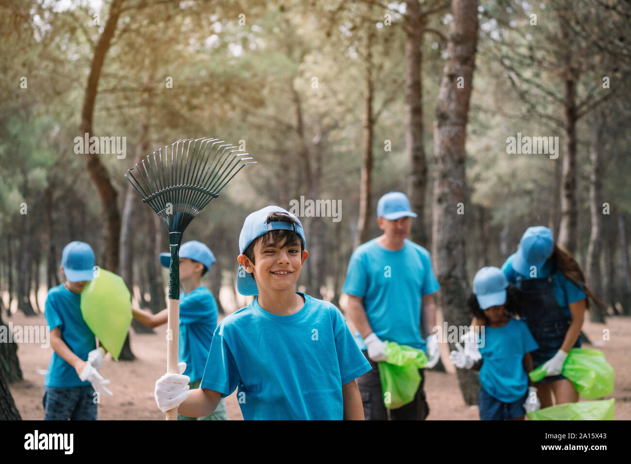 Porträt eines Jungen mit einer Gruppe von Leuten Garbage Collecting in einem Park Stockfoto