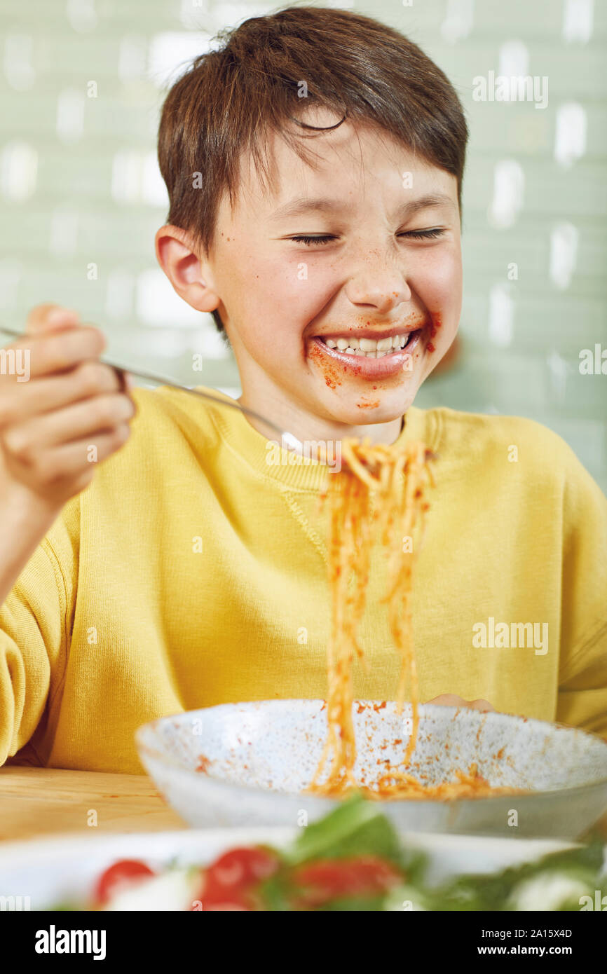 Unordentliche junge Essen Spaghetti mit Tomatensauce. Stockfoto