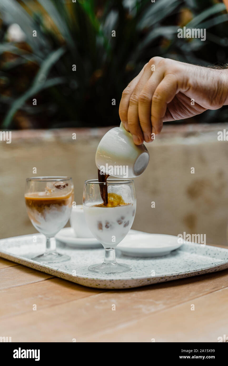 Hand gießen Espresso in ein Glas Stockfoto