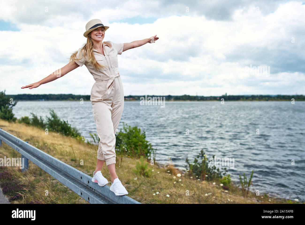 Glückliche Frau Balancieren auf Leitplanke am See Stockfoto