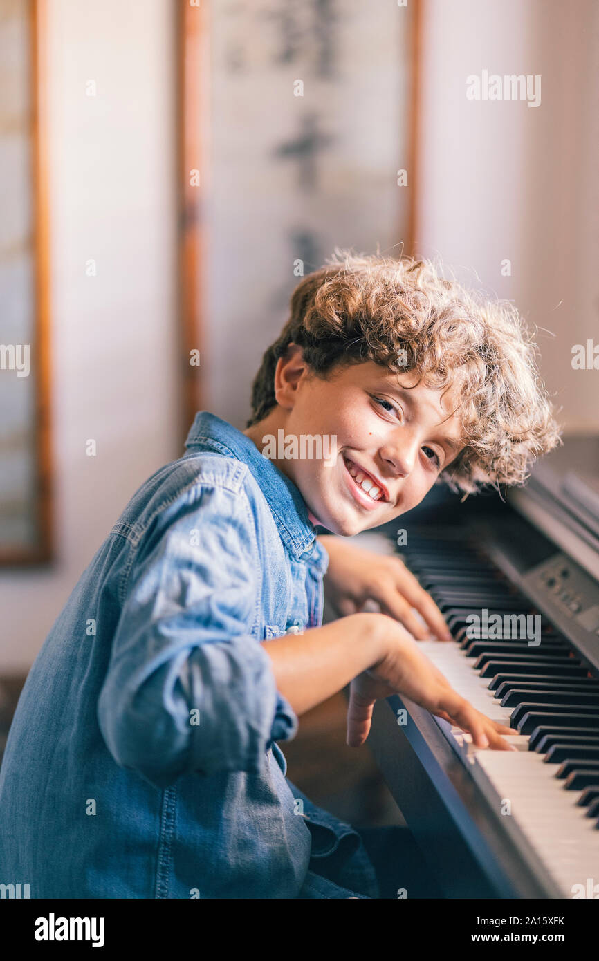 Porträt der lächelnde Junge spielt Klavier zu Hause Stockfoto