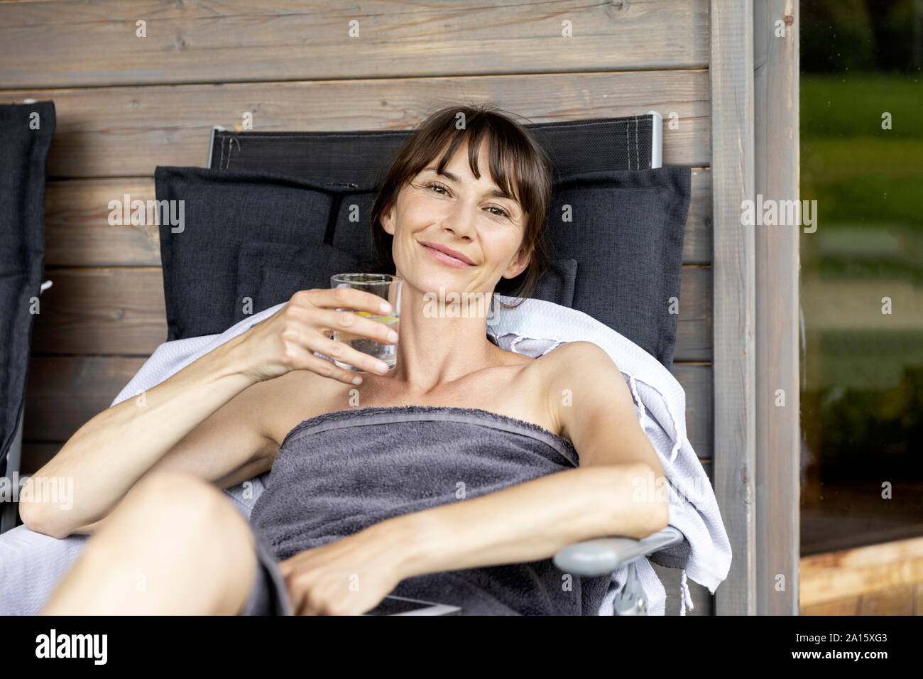 Porträt der Frau, die sich auf einen Wohnbereich mit Glas Wasser Stockfoto
