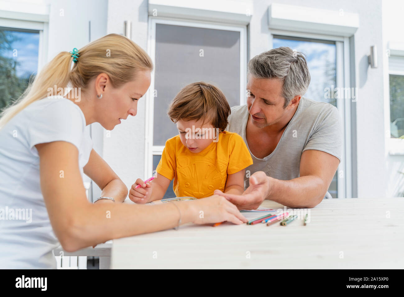 Vater, Mutter und Sohn Hausaufgaben zusammen auf der Terrasse Stockfoto