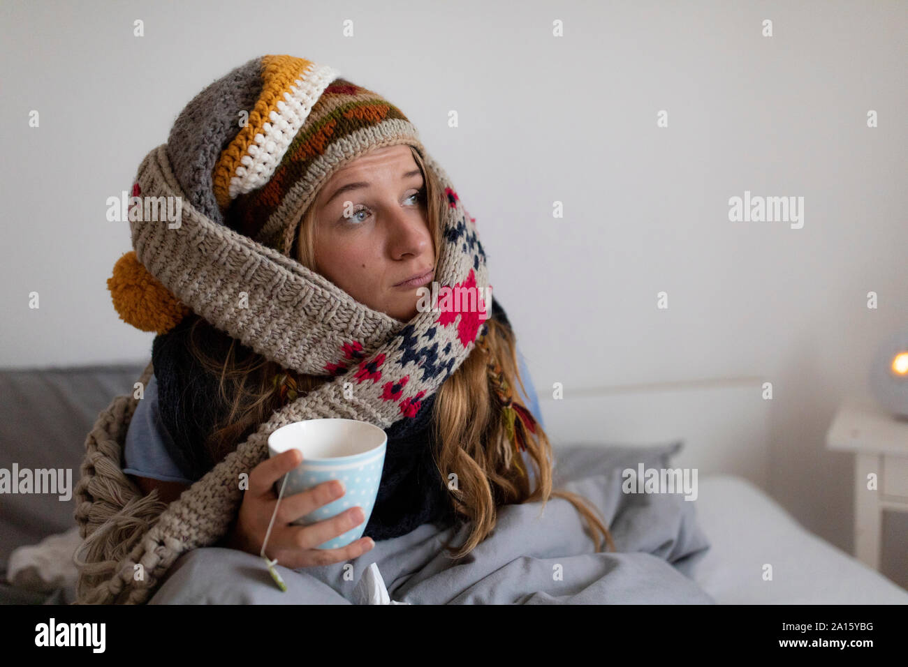 Kranke junge Frau trinkt Tee im Bett zu Hause. Stockfoto