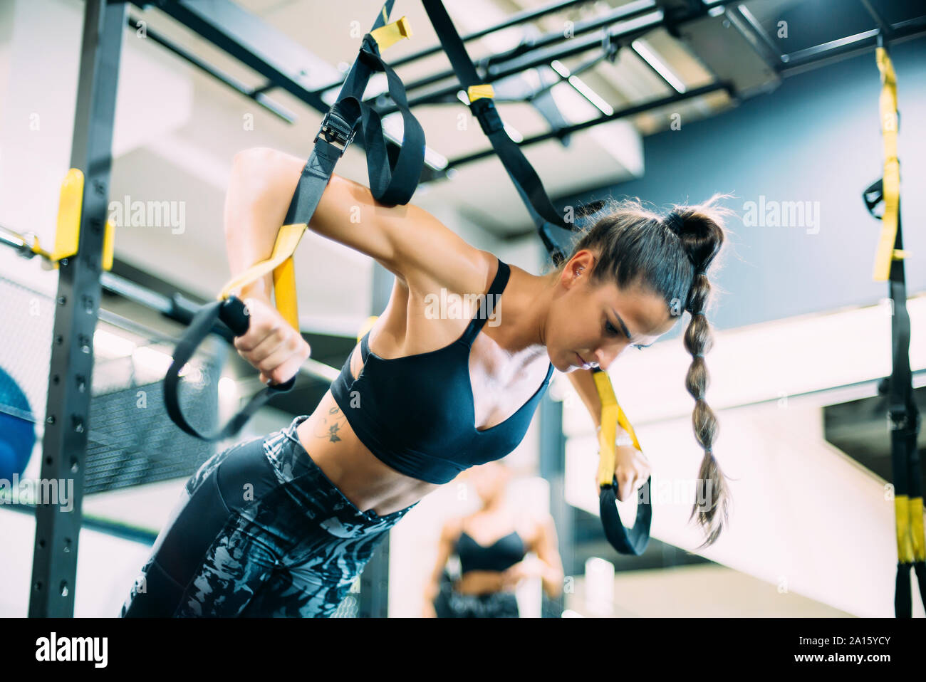 Junge Frau im Fitnessstudio tun Fitness Übungen mit Sport Gurte