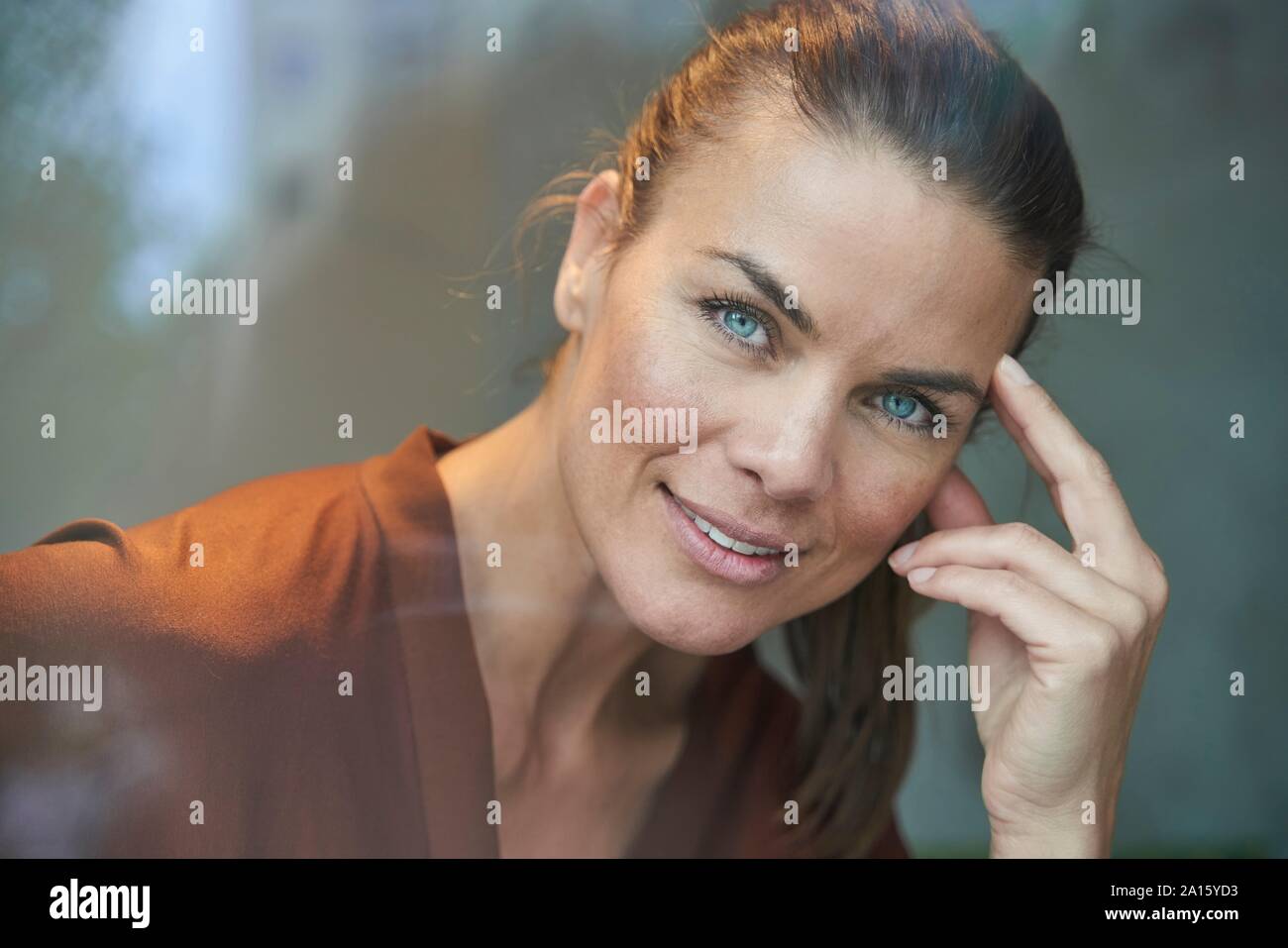 Portrait von lächelnden attraktive Frau hinter Fensterglas Stockfoto