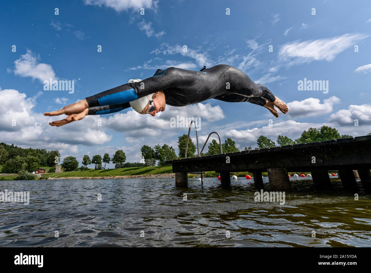 Junge Triathletin in einen See springen Stockfoto