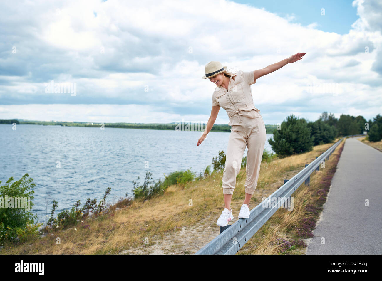 Glückliche Frau Balancieren auf Leitplanke am See Stockfoto
