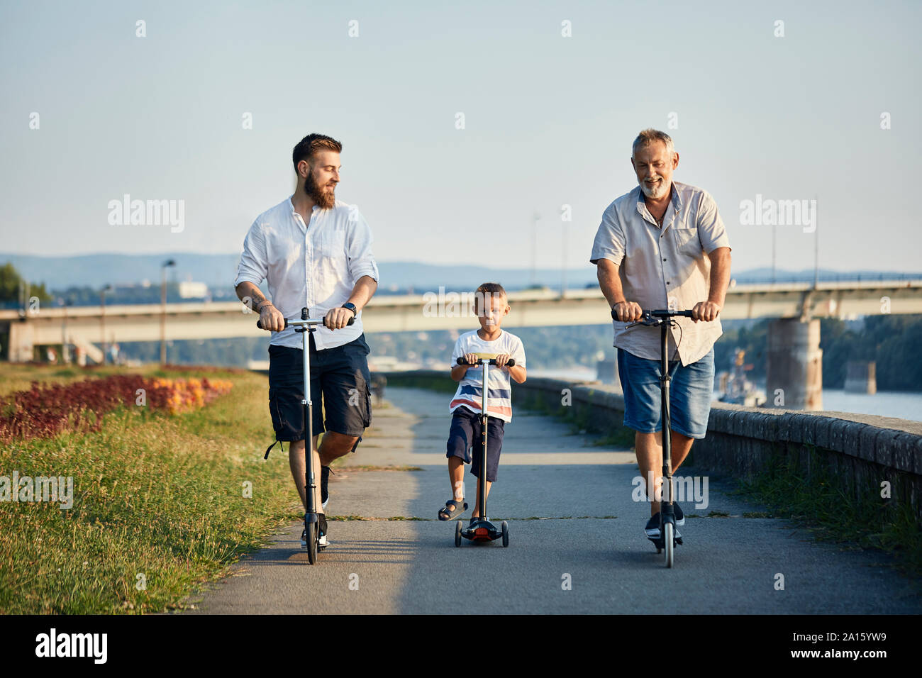 Großvater, Vater und Sohn, Motorroller am Flußufer Stockfoto