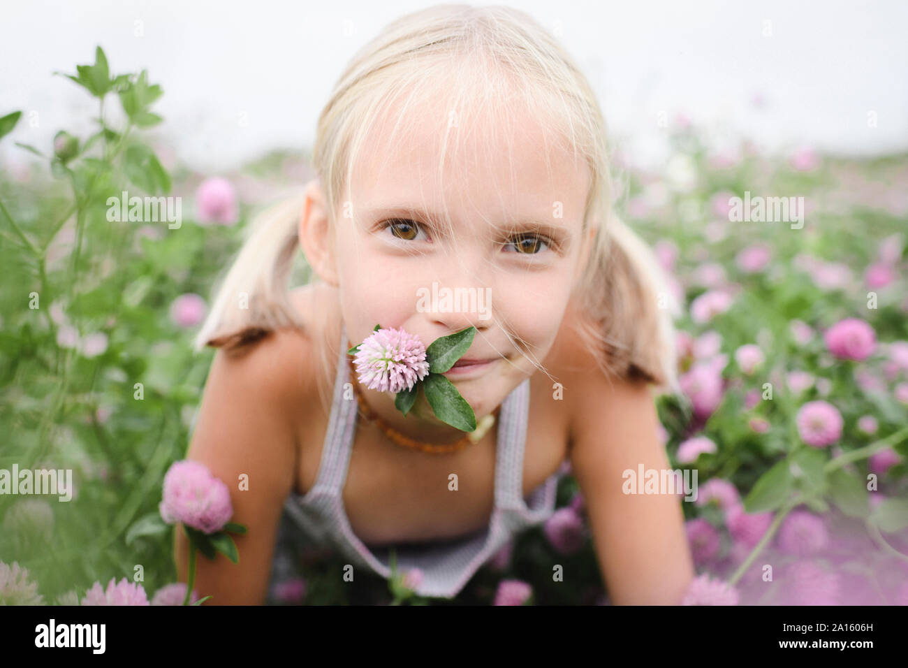 Portrait von lächelnden Mädchen mit Kleeblatt Blume im Mund Stockfoto