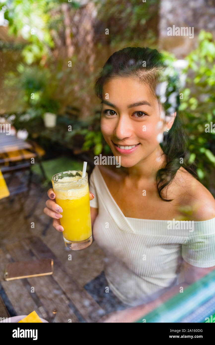 Portrait von lächelnden jungen Frau mit einem gesunden Drink hinter Glasscheibe Stockfoto