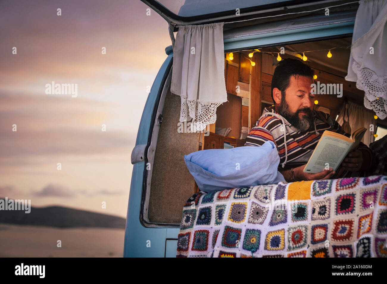 Reifer Mann lag in Van und ein Buch lesen Stockfoto