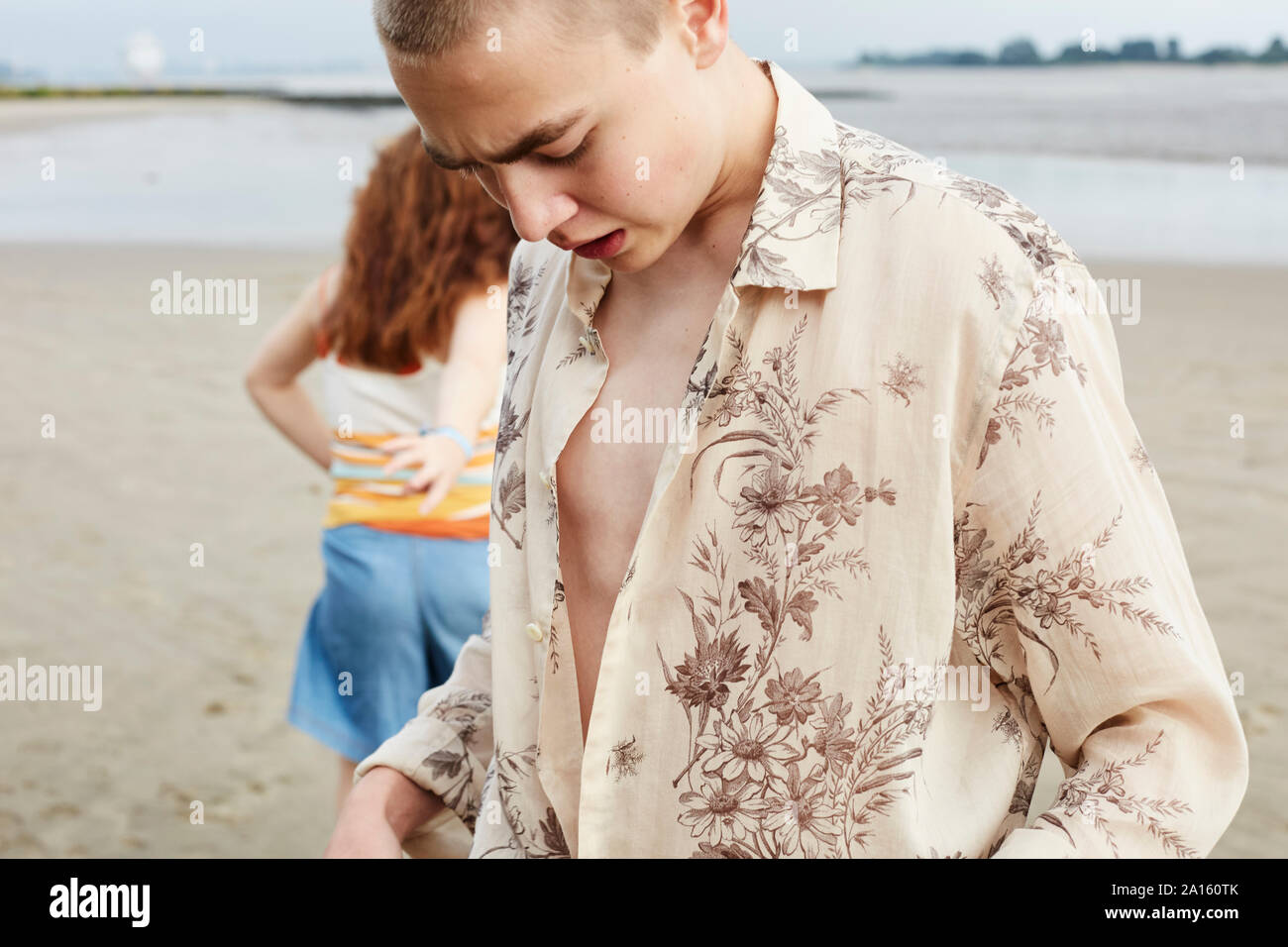Teenager setzen auf T-Shirt am Strand Stockfoto