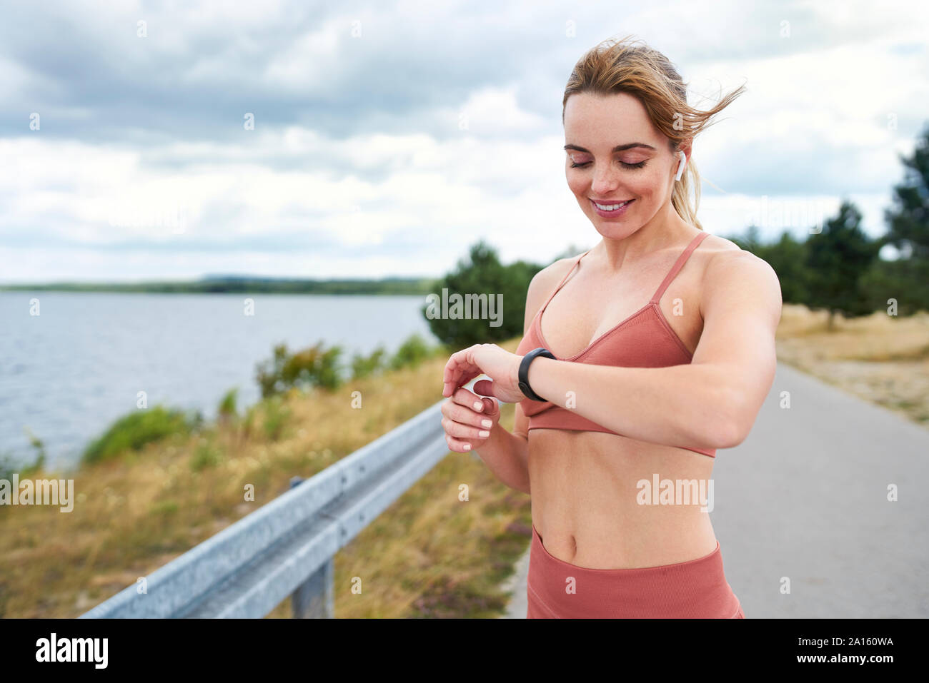 Portrait von passende Frau Kontrolle smartwatch während im Freien joggen Sitzung Stockfoto
