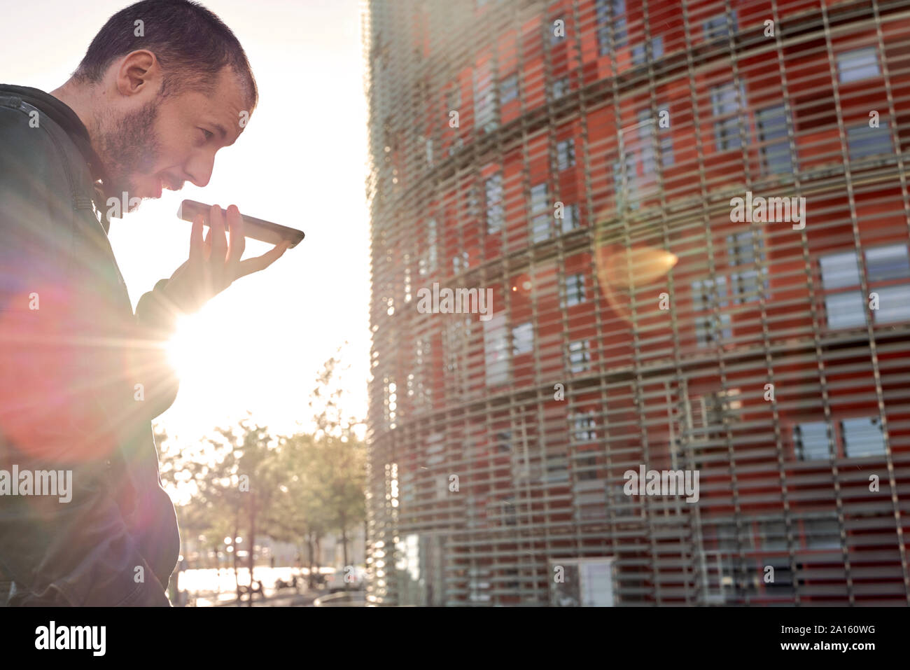 Mann mit Handy bei Sonnenuntergang in der Stadt, Barcelona, Spanien Stockfoto