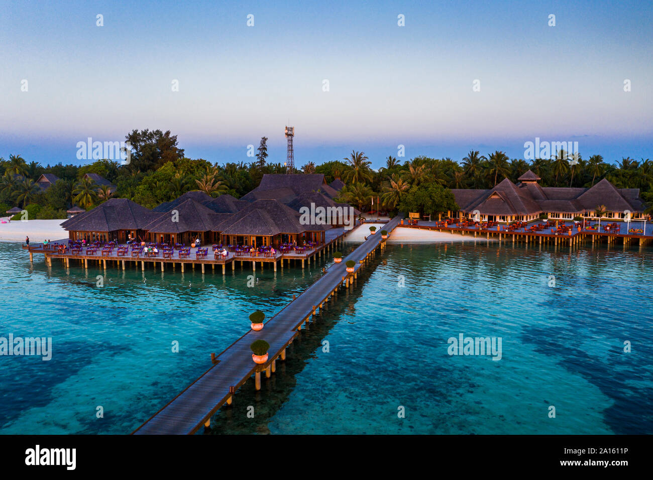 Malediven Olhuveli Island, Pier und Resort Süd Male Atoll Lagune bei Sonnenuntergang Stockfoto