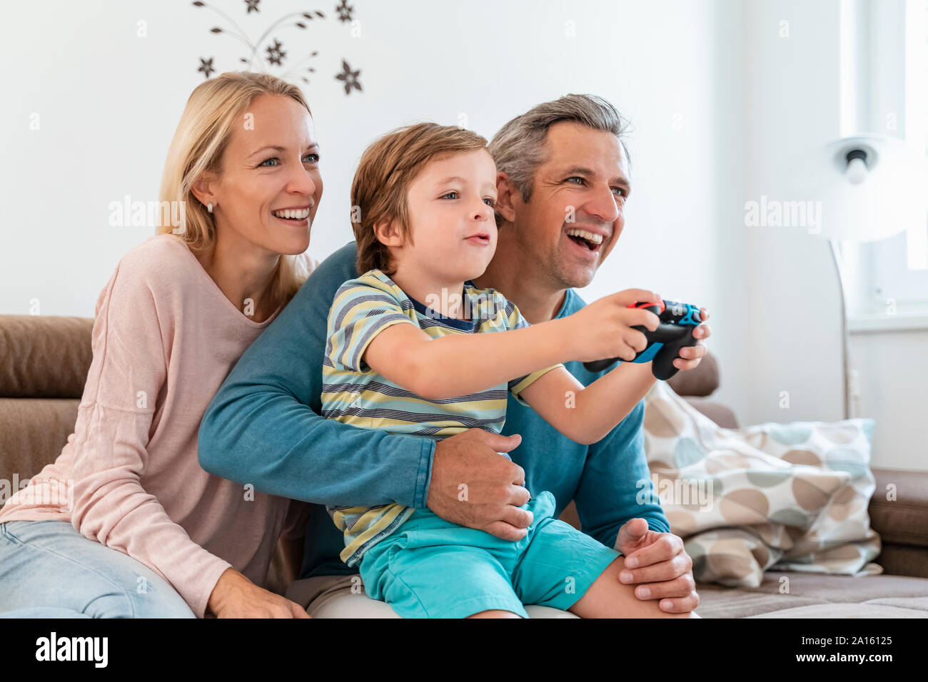 Glückliche Eltern mit Sohn spielen Video Game auf der Couch zu Hause Stockfoto