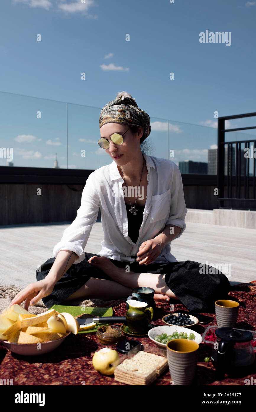 Stilvolle Frau mit Sonnenbrille, eine gesunde Mahlzeit auf dem Dach Stockfoto