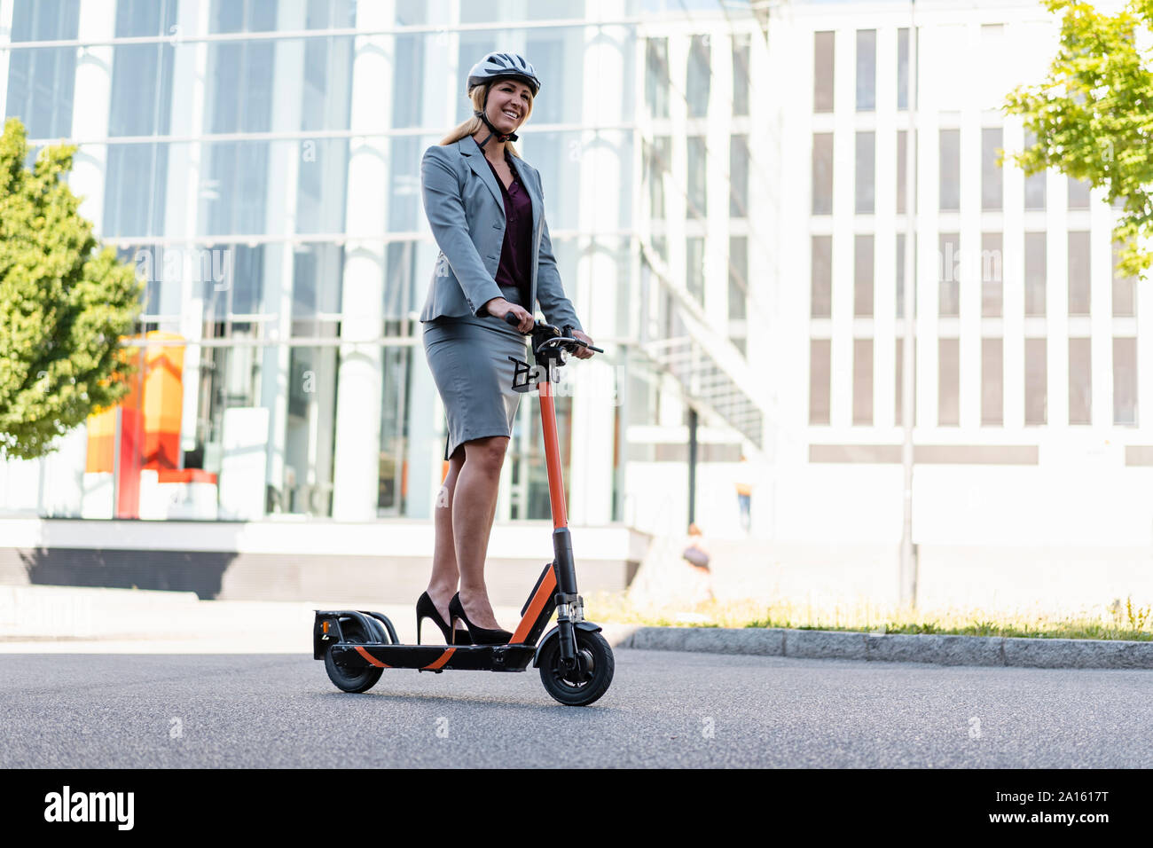 Geschäftsfrau, die das Tragen von High Heels, Elektrische Roller auf der Straße Stockfoto