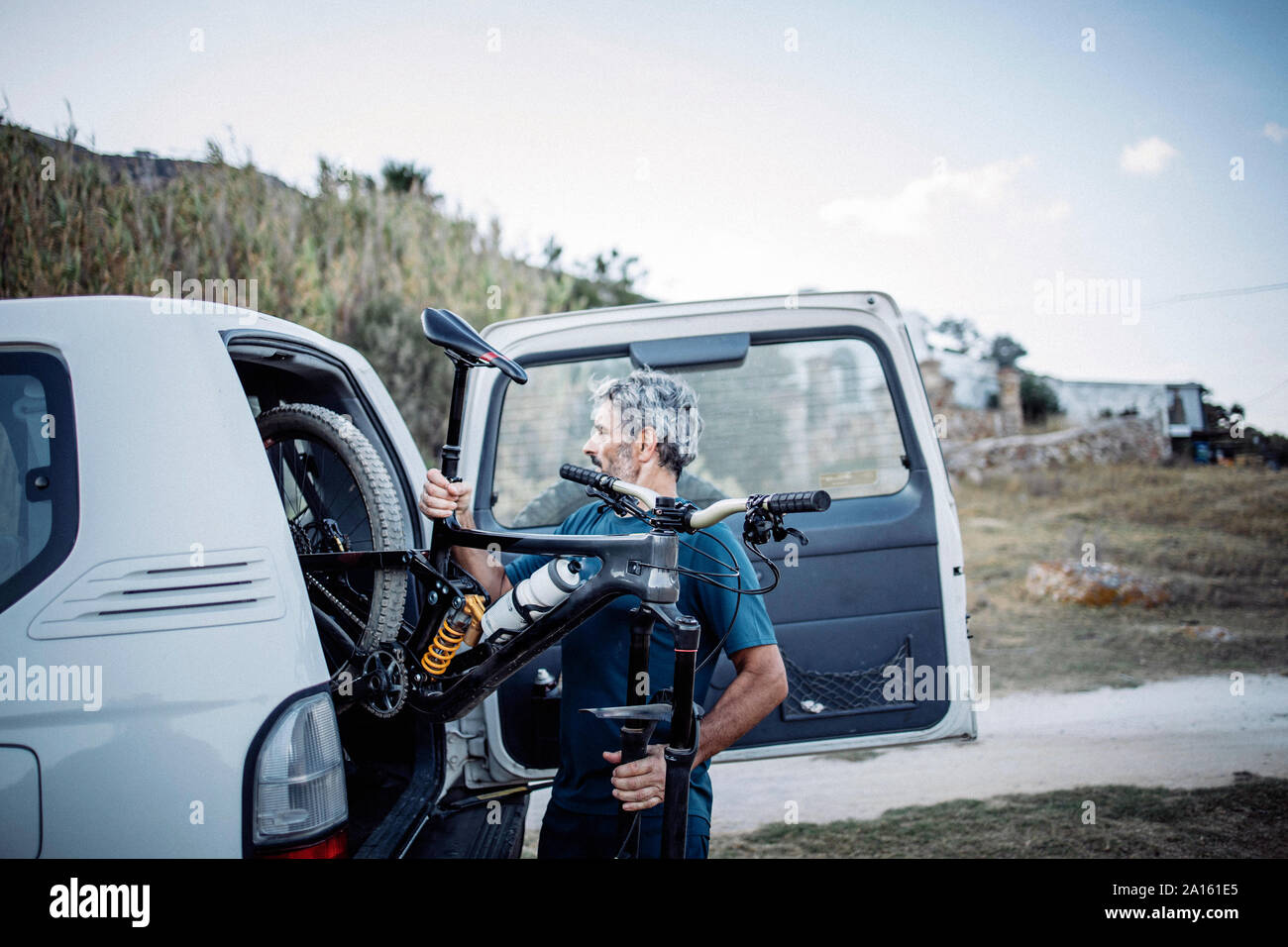 Reifer Mann verstauen Fahrrad in seine Geländewagen. Stockfoto
