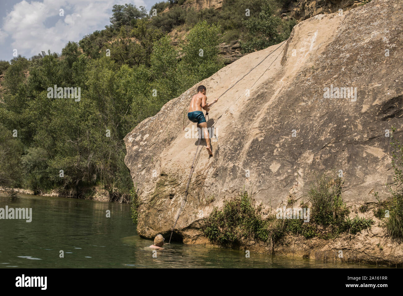 Junger Mann climbimg ein Fels an einem See, Spanien Stockfoto