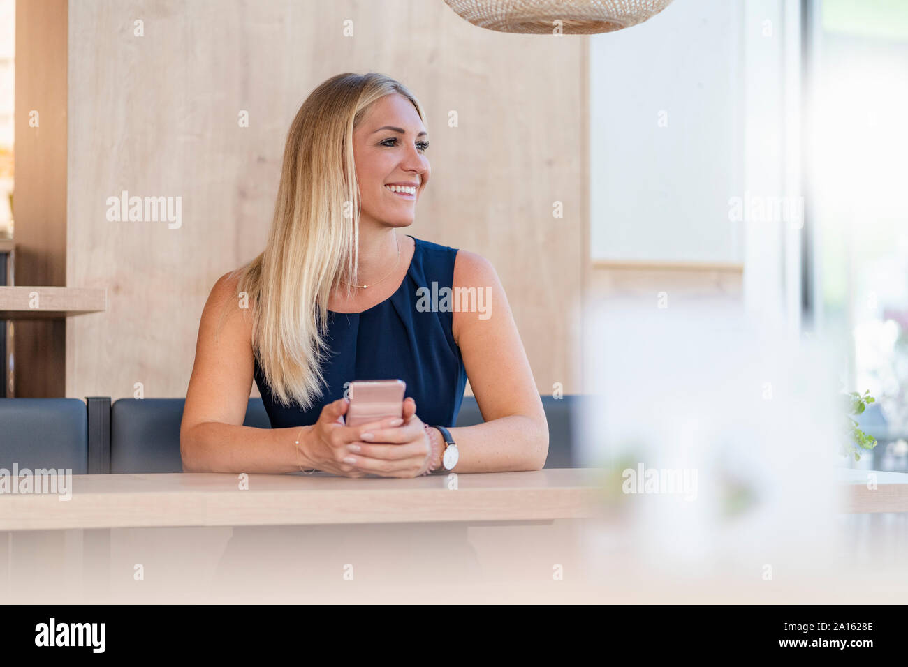 Portrait von lächelnden blond Geschäftsfrau mit Smartphone in einem Café warten Stockfoto