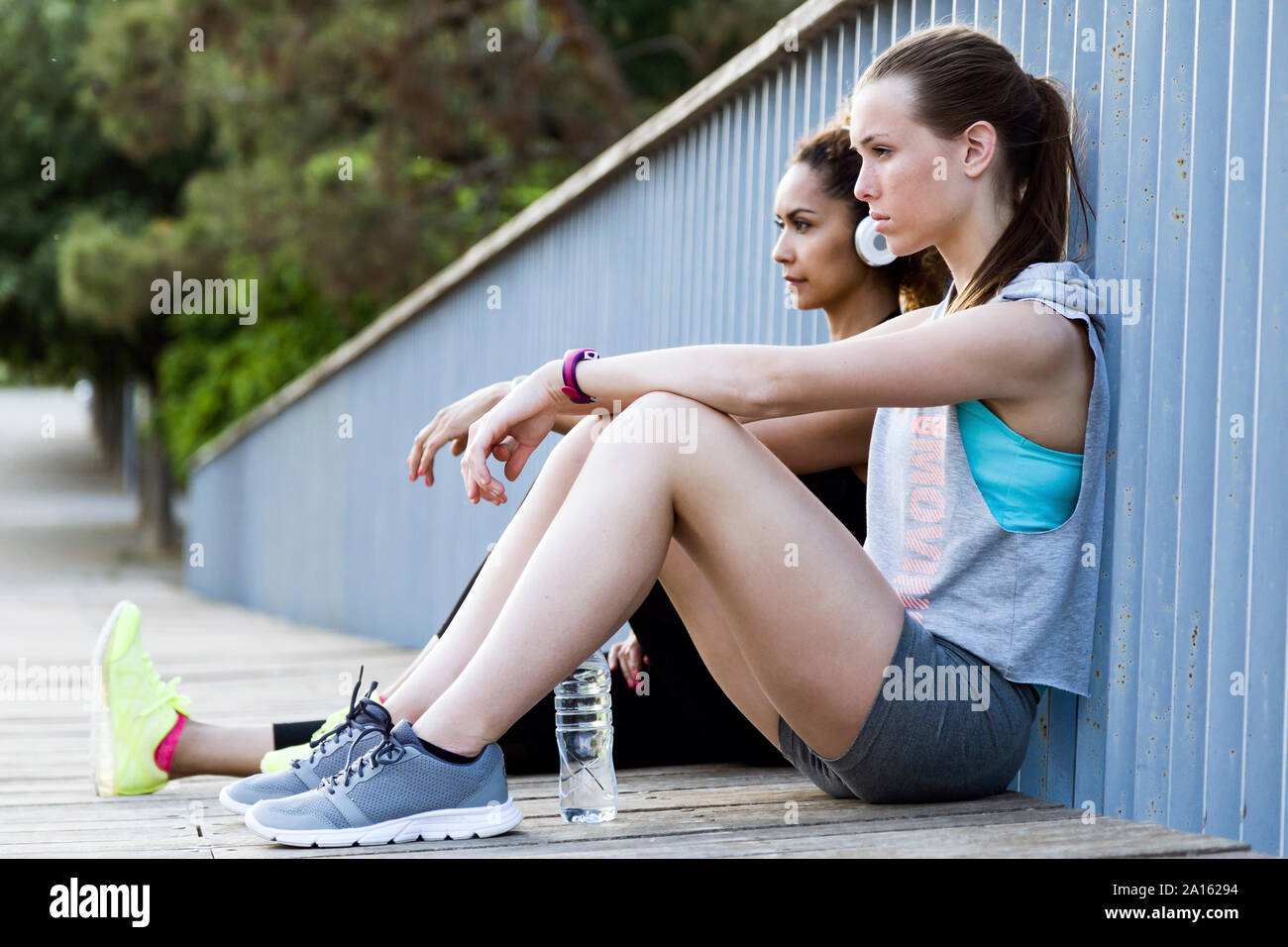 Zwei sportliche junge Frauen entspannen auf einer Brücke nach dem Workout Stockfoto