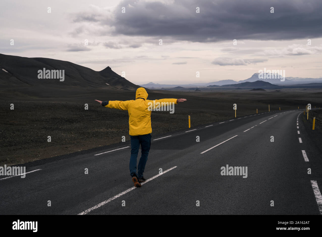 Man Balancieren auf der Mittellinie der leere Straße, Island Stockfoto