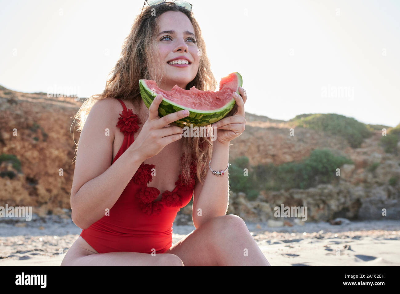 Glückliche junge Frau mit Wassermelone Schicht am Strand Stockfoto