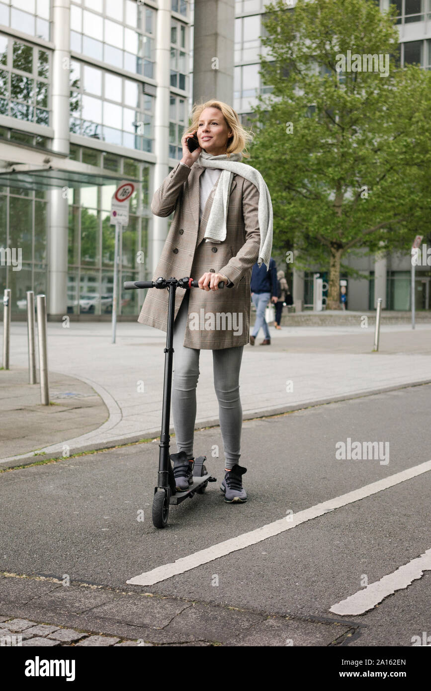 Junge Frauen reiten Elektroroller auf der Straße Stockfoto