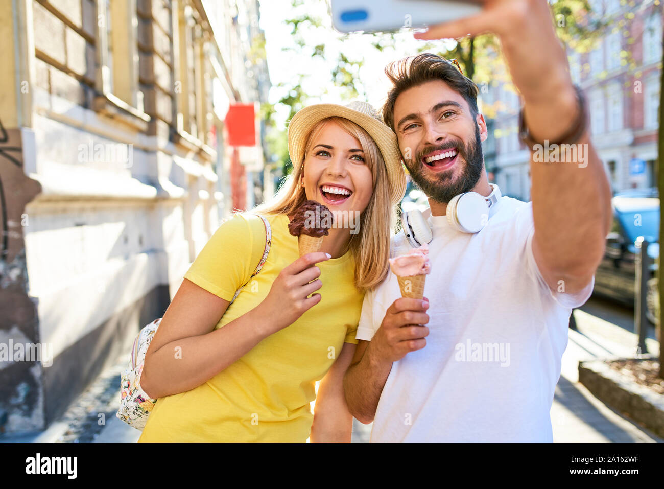 Glückliches junges Paar ein selfie während Eis essen in der Stadt Stockfoto