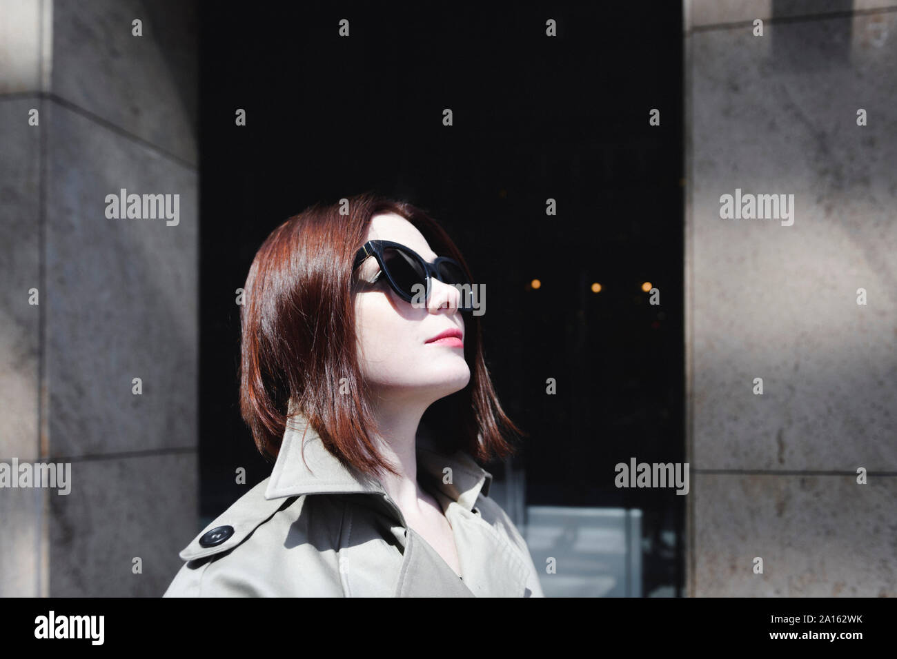 Porträt einer stilvollen Frau mit Sonnenbrille und Trenchcoat Stockfoto