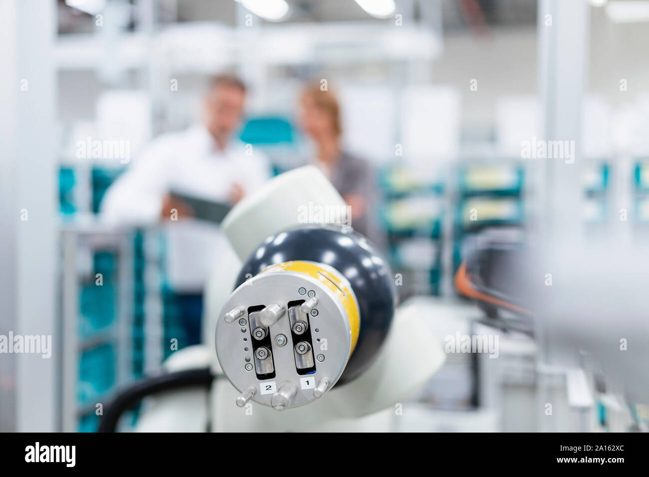Montage Roboter in einer Fabrik mit Geschäftsleuten in Hintergrund Stockfoto