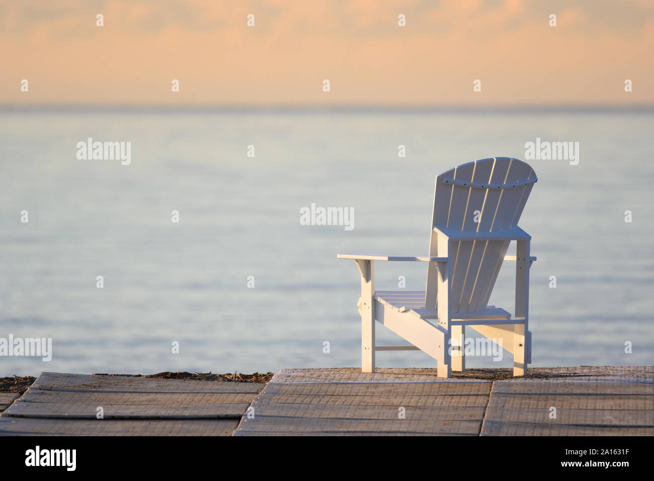 Ein muskoka Chair mit Blick auf Lake Ontario während einer warmen Spät - Sommer Sonnenaufgang am Toronto, Ontario Woodbine Strand. Stockfoto
