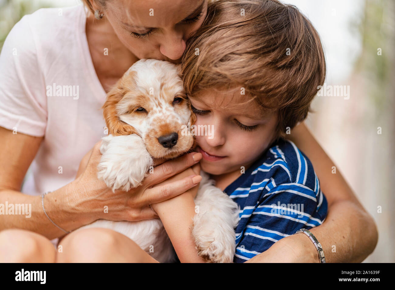 Mutter und Sohn Kuscheln mit niedlichen Hund Welpe Stockfoto