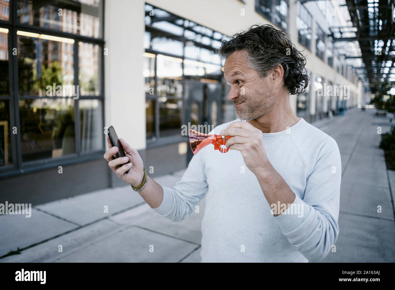 Portrait von reifer Mann mit Horn und Smartphone Stockfoto