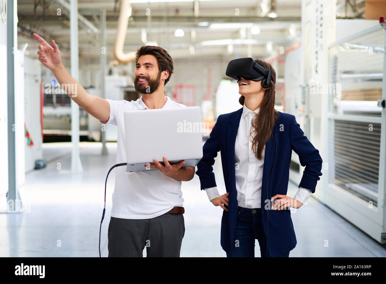 Mann mit Laptop und Geschäftsfrau tragen VR-Brille in der Factory Stockfoto