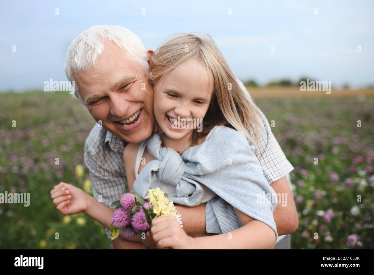 Porträt der glückliche Großvater und Enkelin mit gepflückten Blumen auf einer Wiese Stockfoto