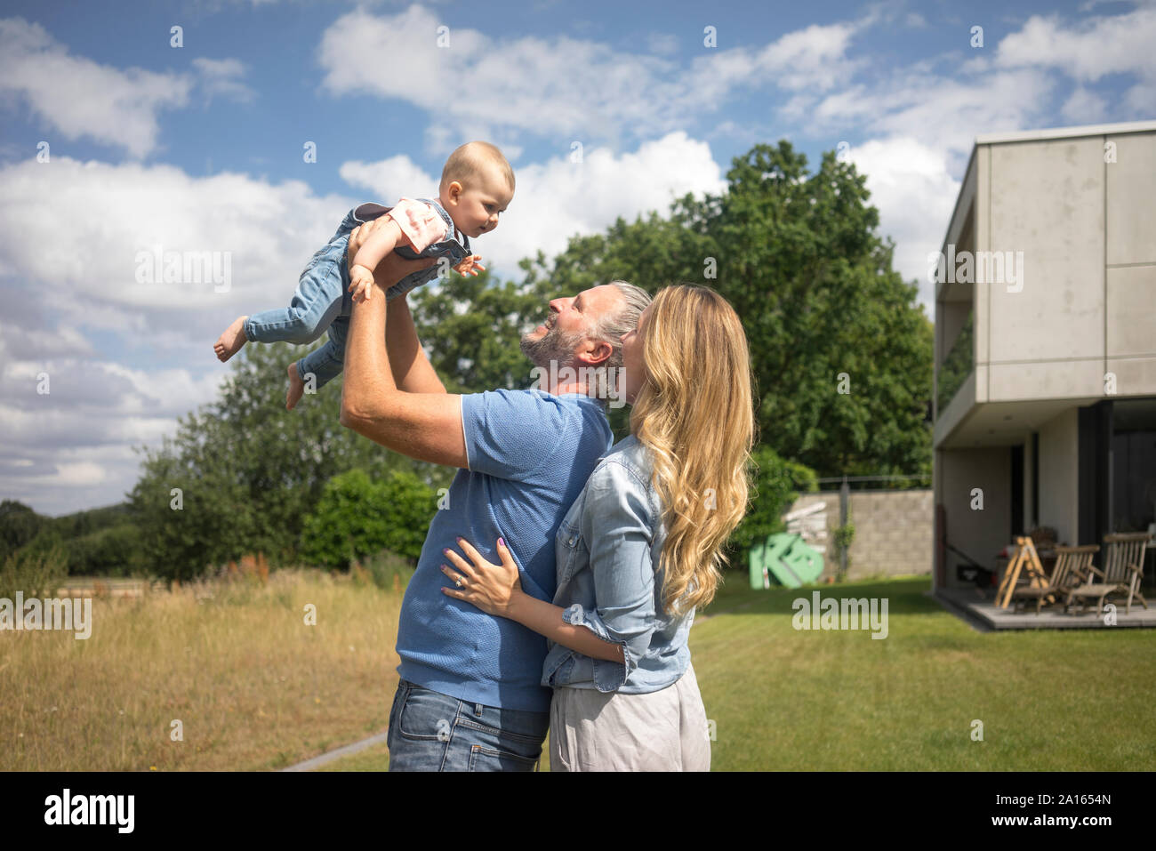 Gerne Vater mit Mutter anheben Baby Mädchen im Garten Stockfoto