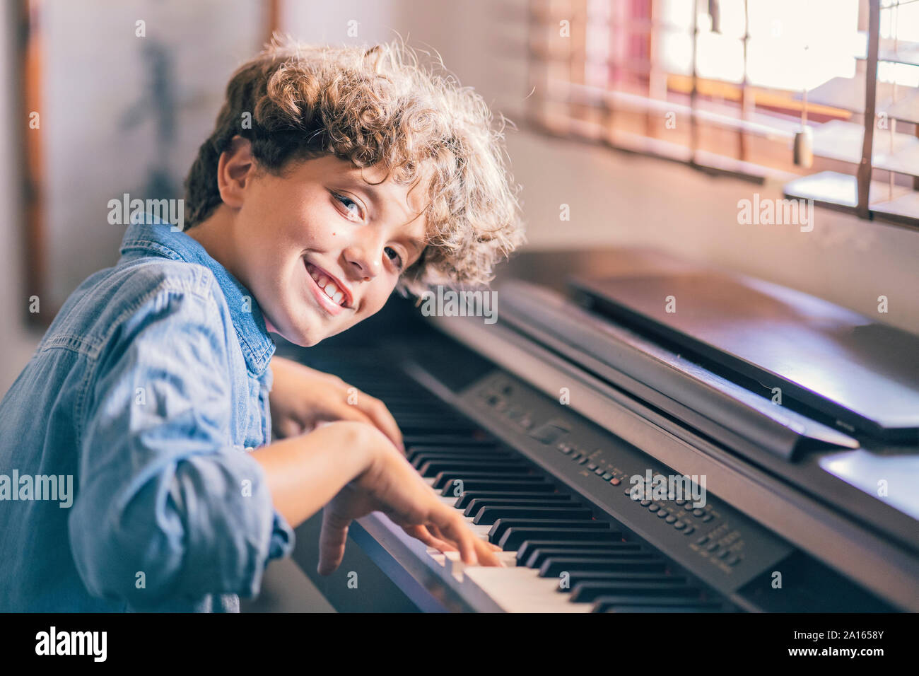 Porträt der lächelnde Junge spielt Klavier zu Hause Stockfoto
