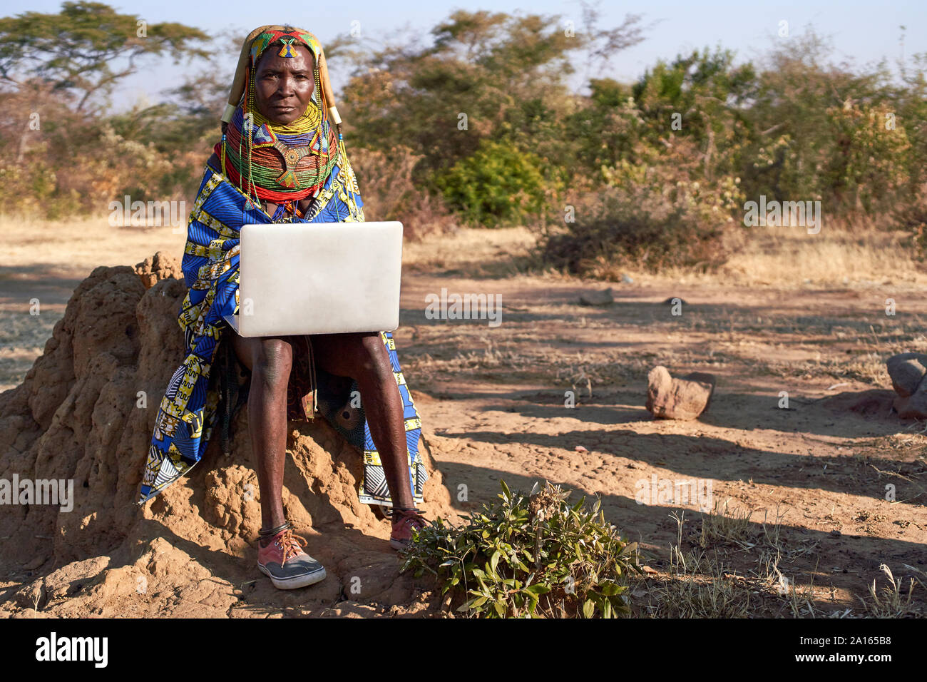 Traditionelle Muhila Frau, Turnschuhe tragen, Neakers arbeitet sie an ihrem Laptop, Kehamba, Chibia, Angola Stockfoto