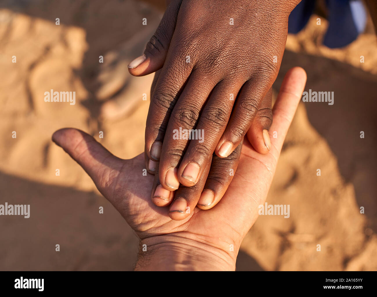 Schwarze Hände schütteln weiße Hände. Mucubal Stamm, Tchitundo Hulo, Angola Stockfoto
