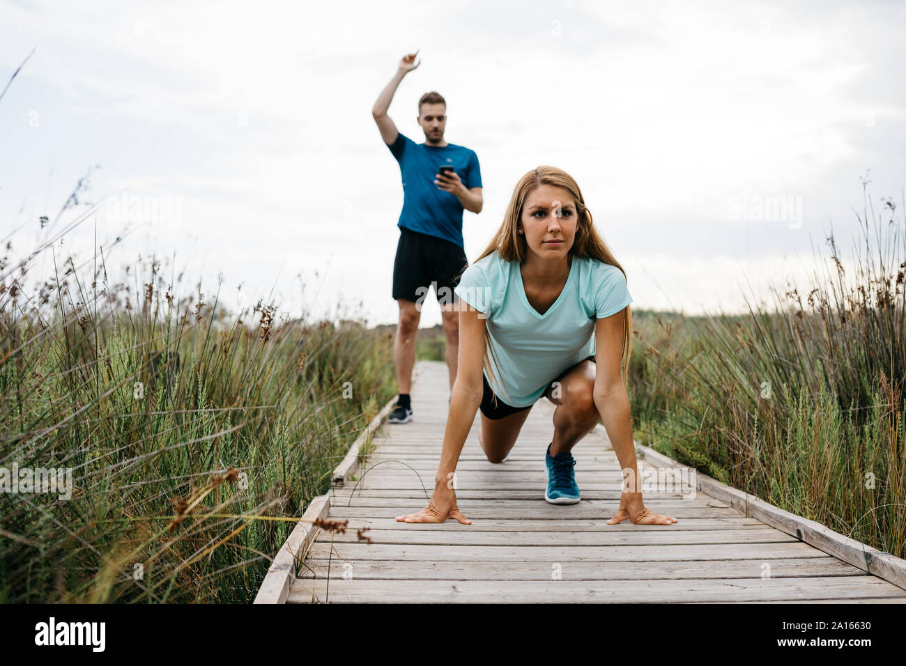 Weibliche Jogger mit Ihrem Trainer auf einem Holzsteg Stockfoto