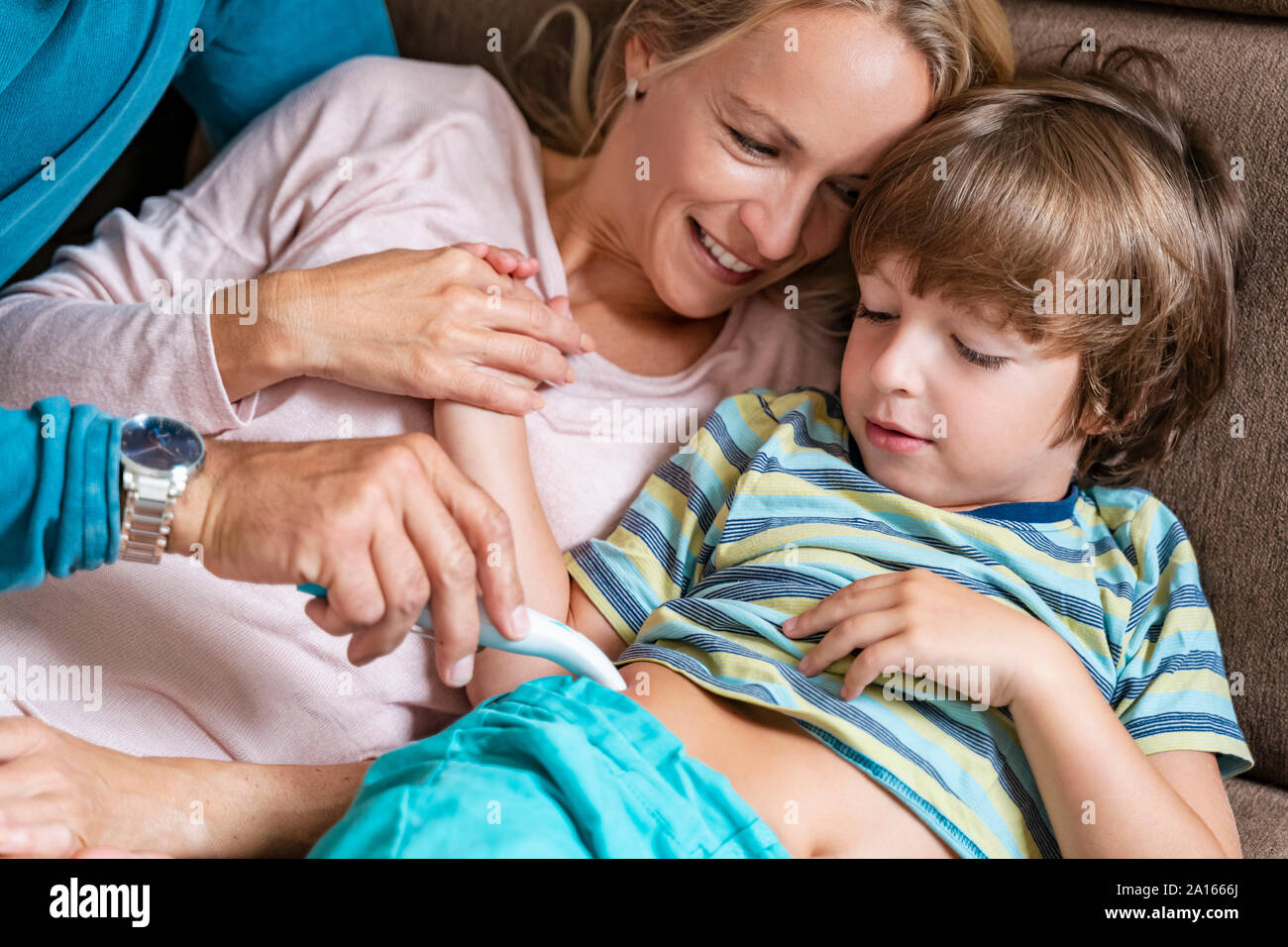 Eltern mit elektronischen sting Heiler für Sohn auf der Couch Stockfoto