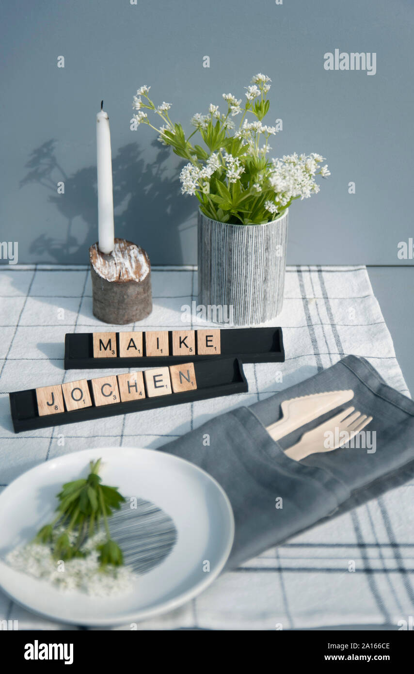Festliche Tischdekoration mit Waldmeister Blumen und Holz- Besteck Stockfoto