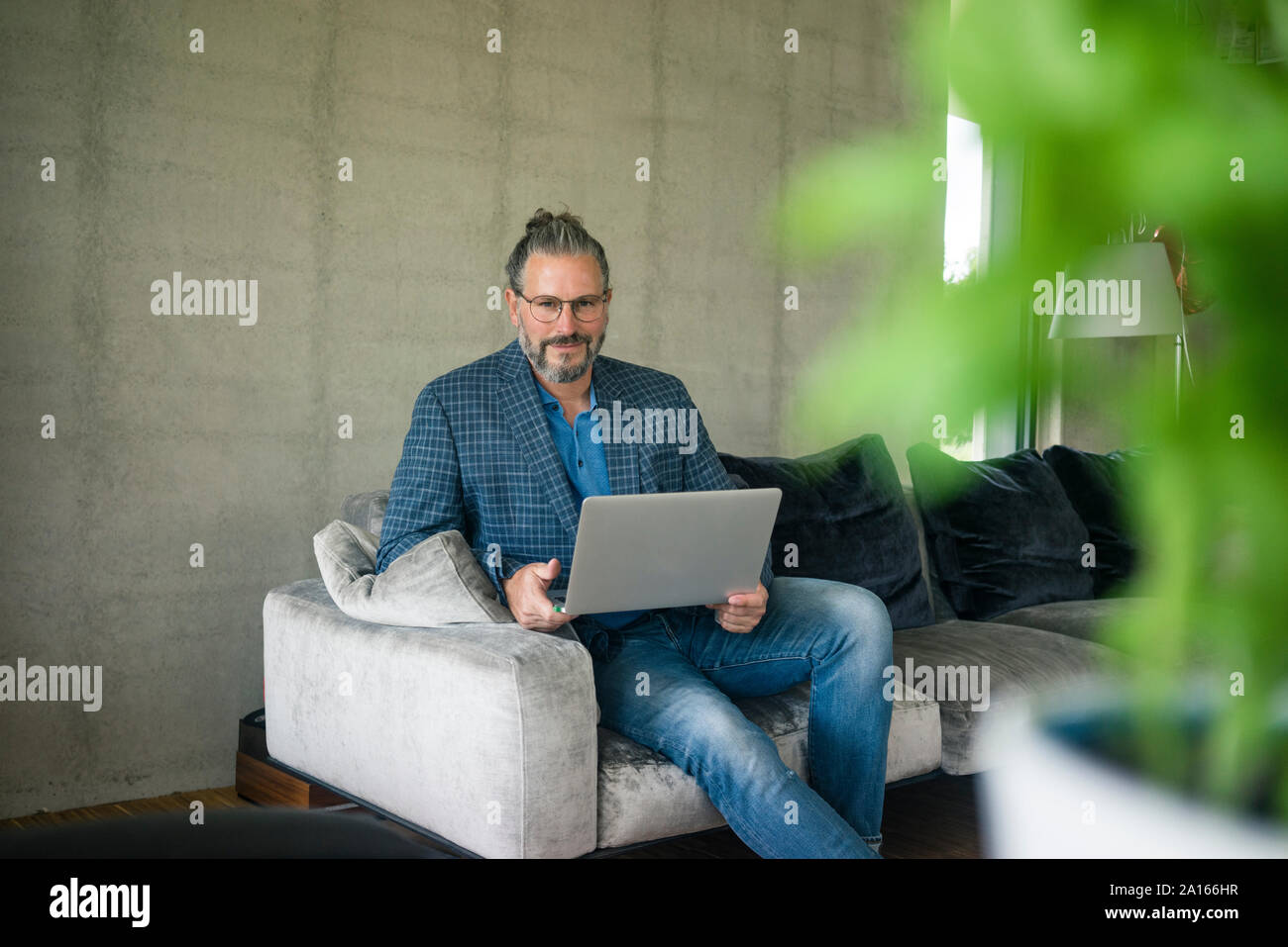 Portrait von Reifen Geschäftsmann auf der Couch zu Hause sitzt mit Laptop Stockfoto