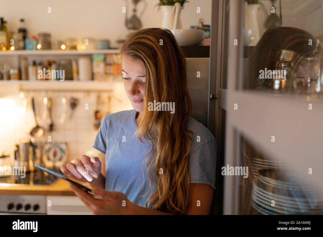 Junge Frau in der Küche zu Hause mit der Tablette Stockfoto