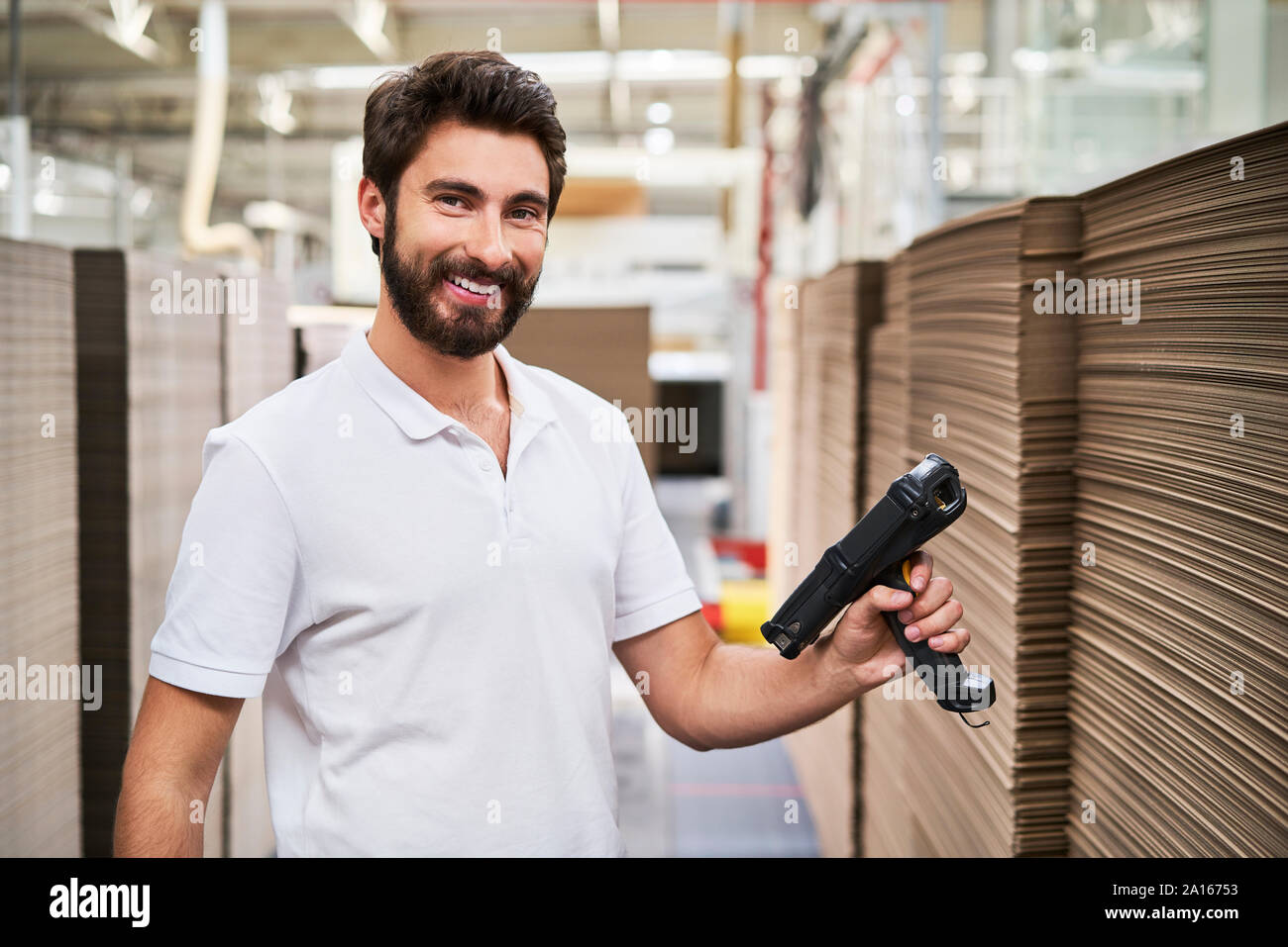 Portrait von lächelnden Mann in Halle mit Barcode Scanner Stockfoto